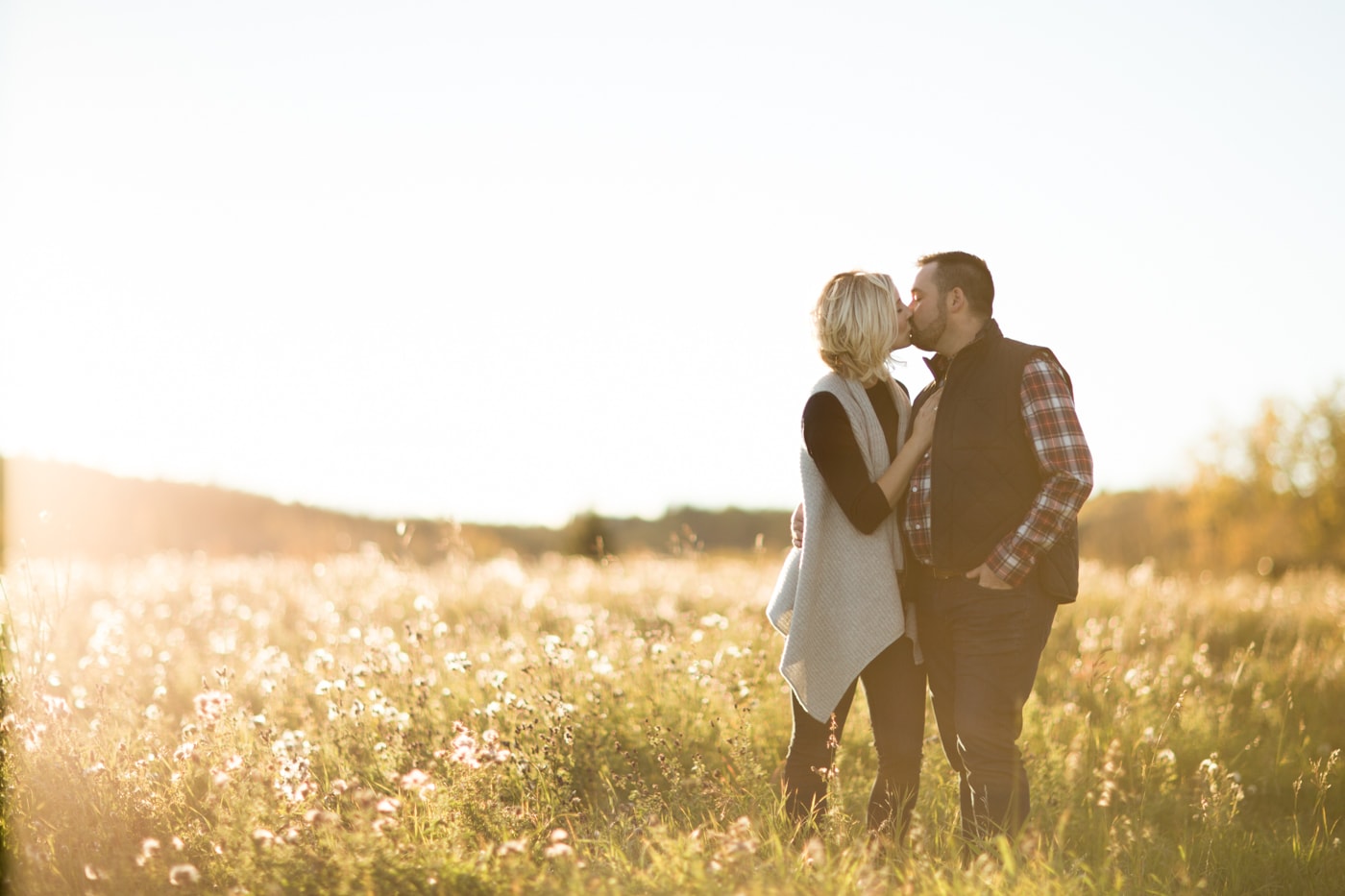 Fall engagement session in Calgary, Alberta with beautiful backlighting and a newly engaged couple kissing as the sun sets