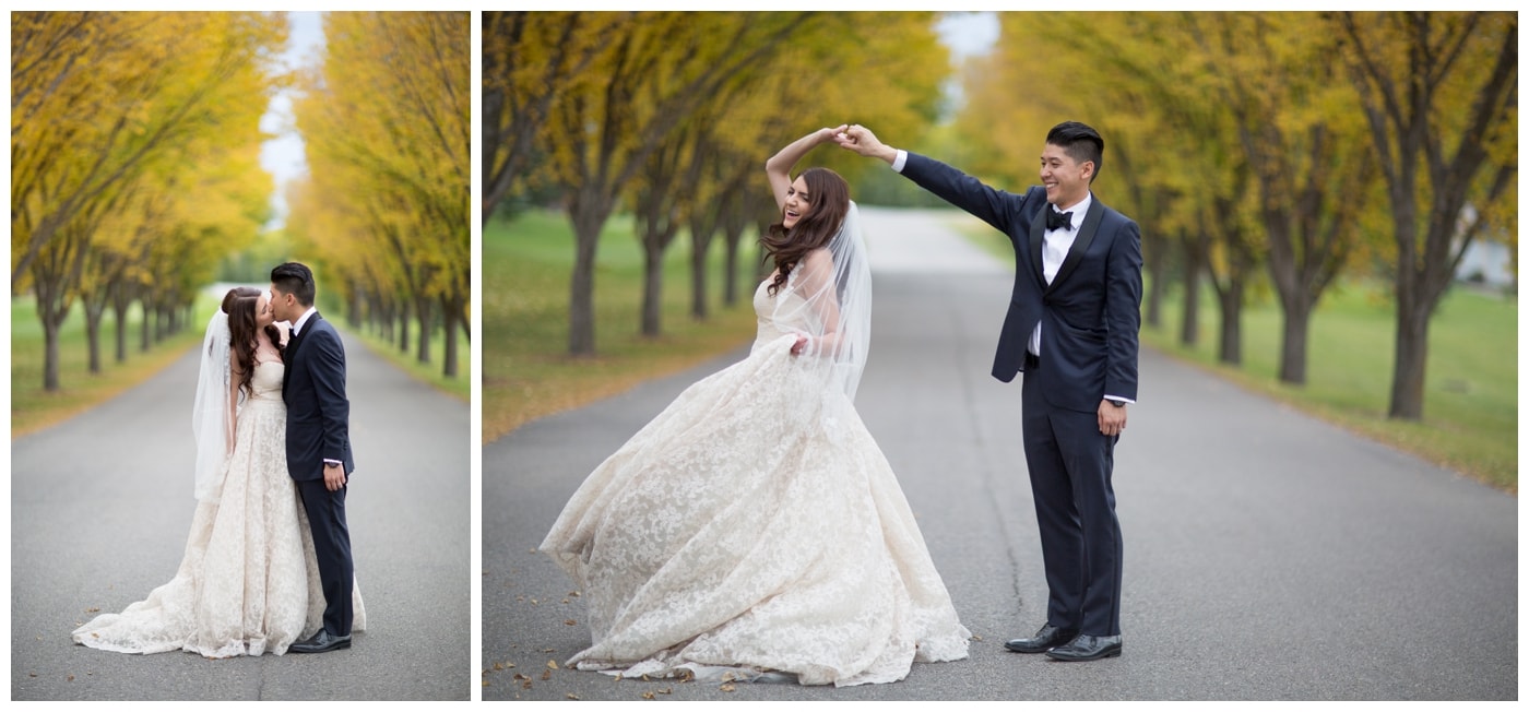 A bride and groom kiss in a roadway lines with beautiful bright yellow fall leaves