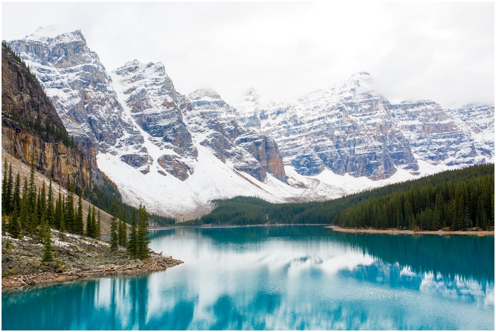 Moraine Lake showing off goreous blue waters, green forests, and massive mountains in the background