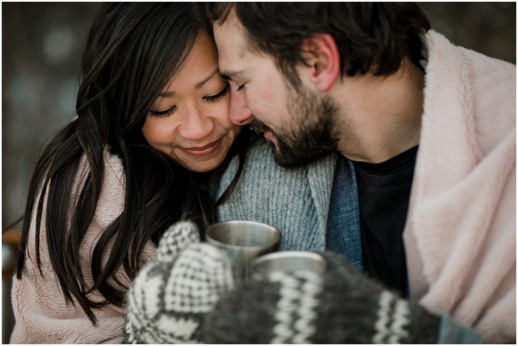 A wedding couple dressed in warm winter clothing cozy's up with a picnic 