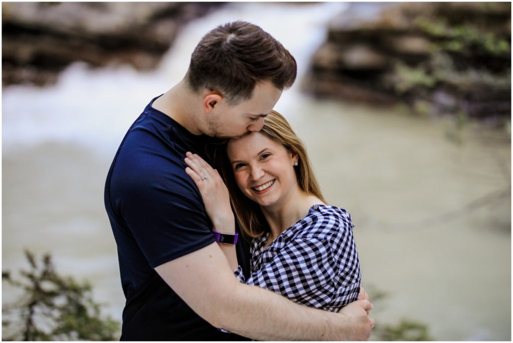 A couple embraces in front of a river at Johnston's Canyon in Banff National Park