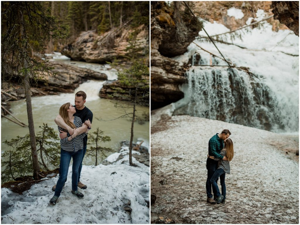 A couple stands in front of the cave and waterfall at Johnston's Canyon in Banff National Park