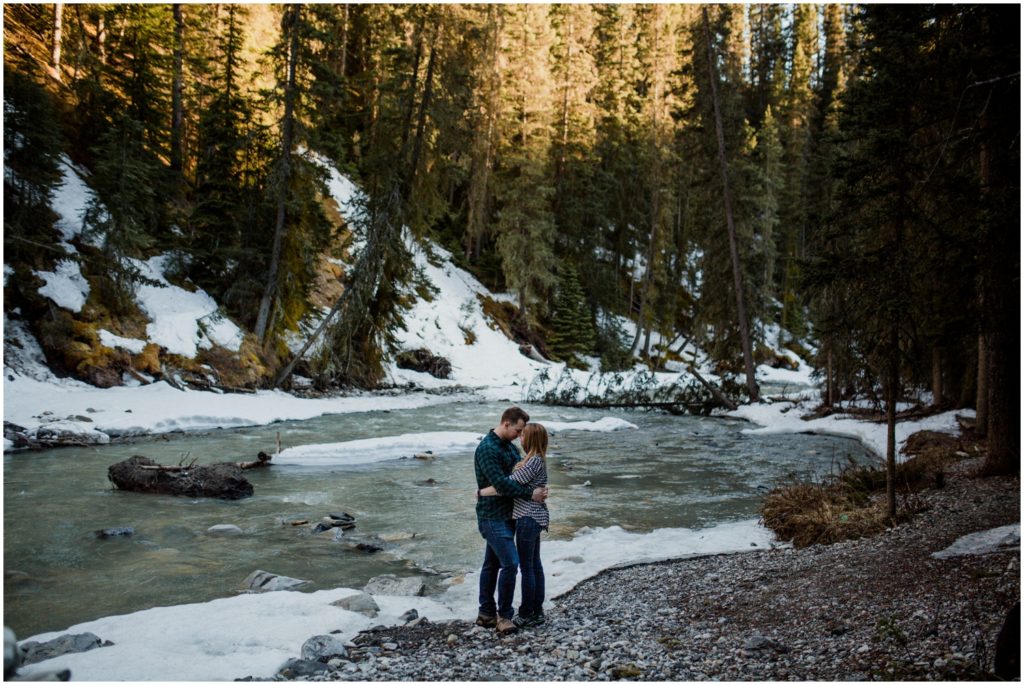 A couple stands in front of a river at Johnston's Canyon in Banff National Park