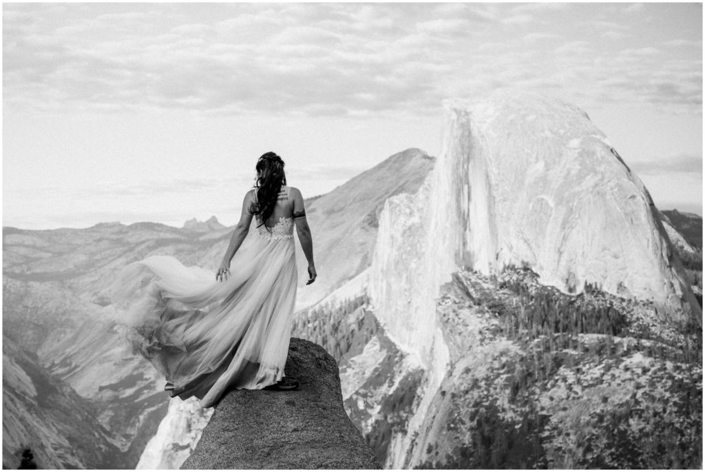 A bride fans her dress while overlooking Half Dome in Yosemite National Park