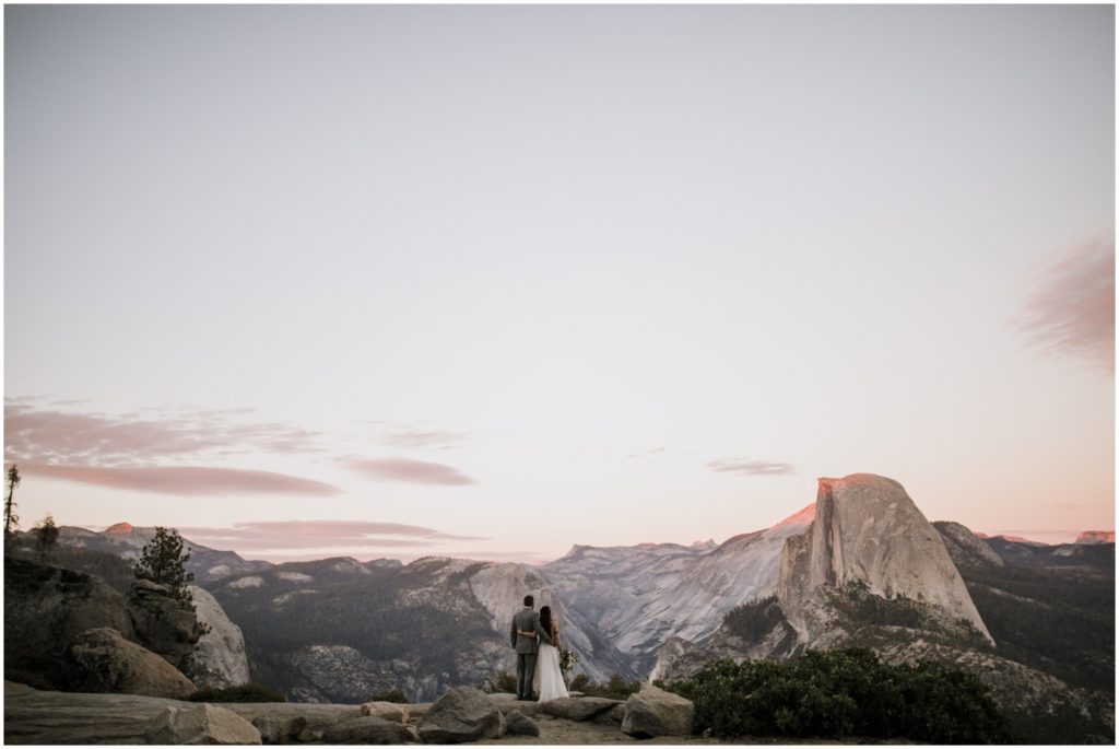 A newly wed couple gazes over sunset at Yosemite National Park whil