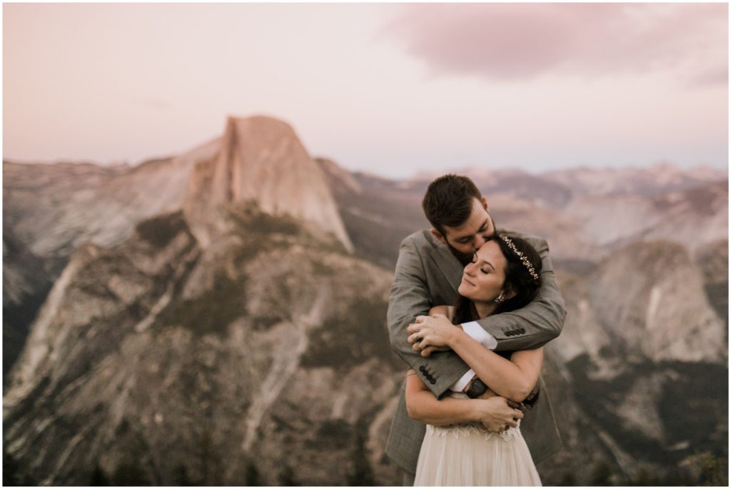 A newly wed couple embraces during sunset overlooking Yosemite National Park