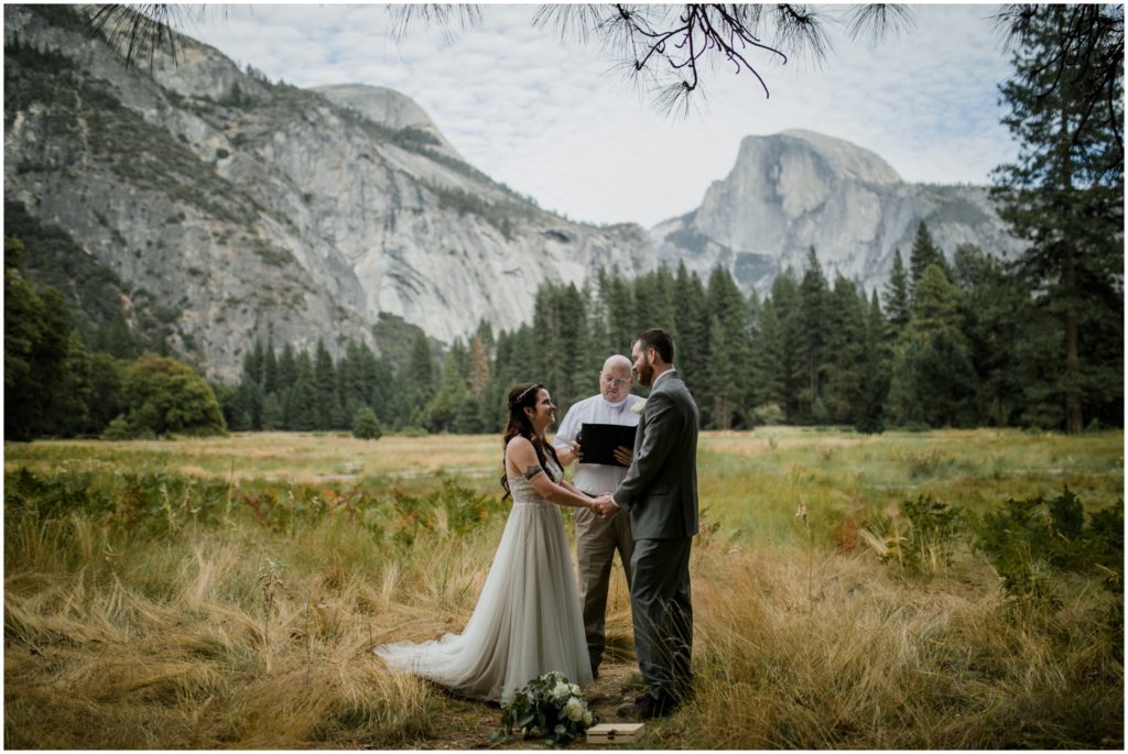 A couple stands in front of an officiant during their ceremony in Yosemite National Park