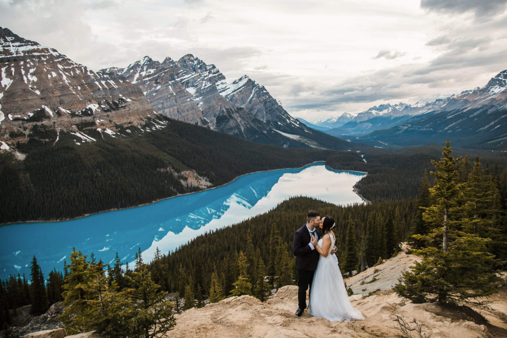 A married couple embraces on a rock overhanging Peyto Lake in Yoho National Park at sunset