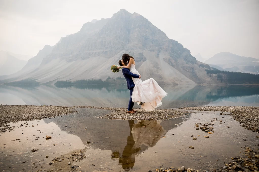 An elopement couple embraces in front of Bow Lake in Banff National Park