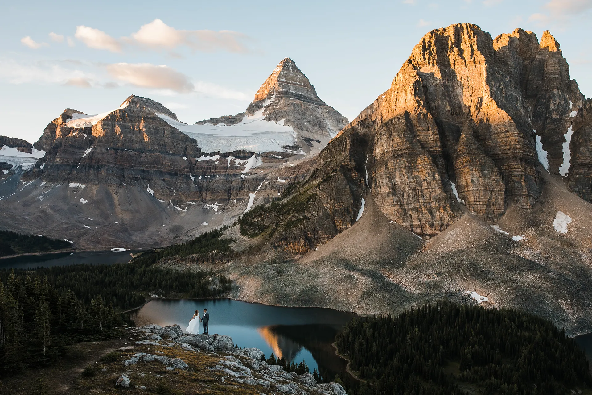 A couple stands in front of Mount Assiniboine at sunrise for their elopement