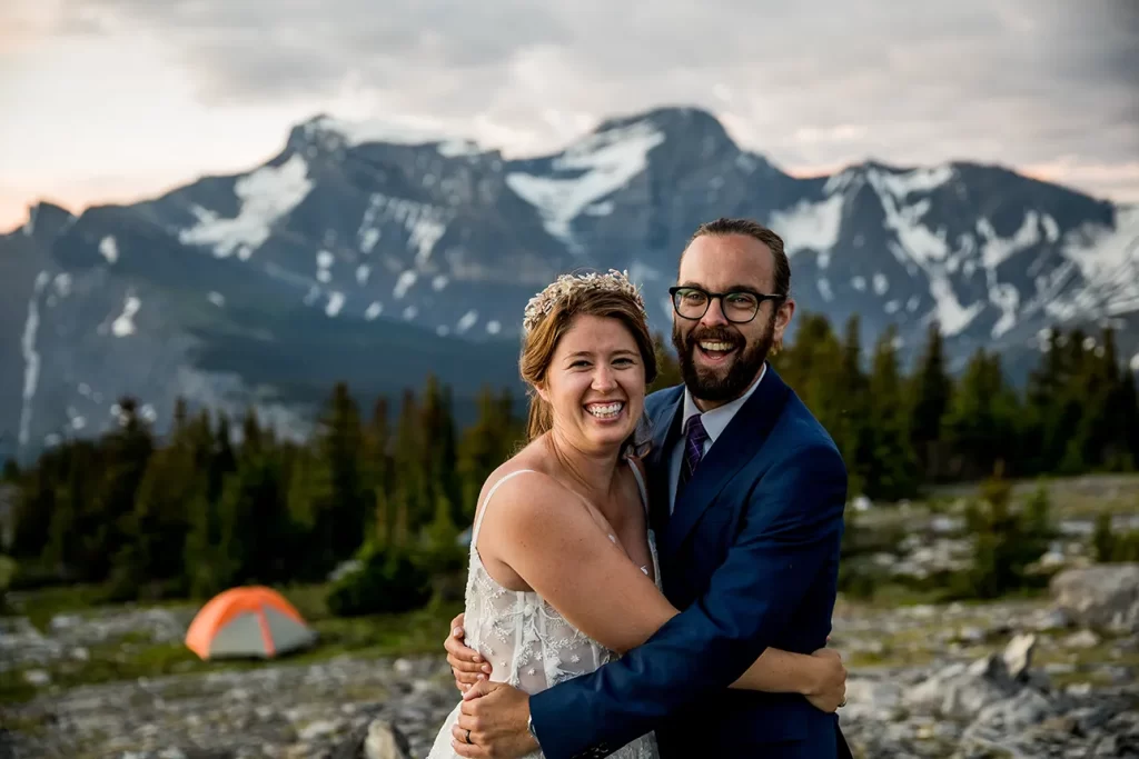 A wedding couple stand in front of their tent during their backcountry hiking elopement