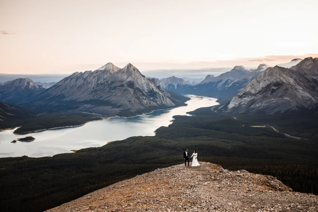 A wedding couple holds hands on Tent Ridge overlooking Spray Lakes Reservoir during their hiking elopement in Banff National Park