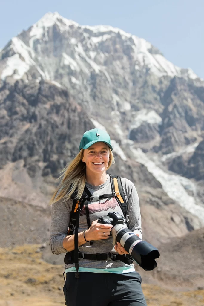 A photographer stands in front of the Andes Mountains of Peru