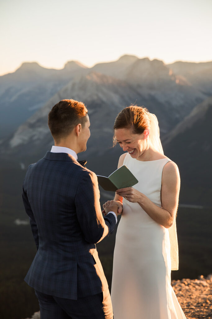 a same sex couple reads their vows during their sunrise hiking elopement on tent ridge kananaskis