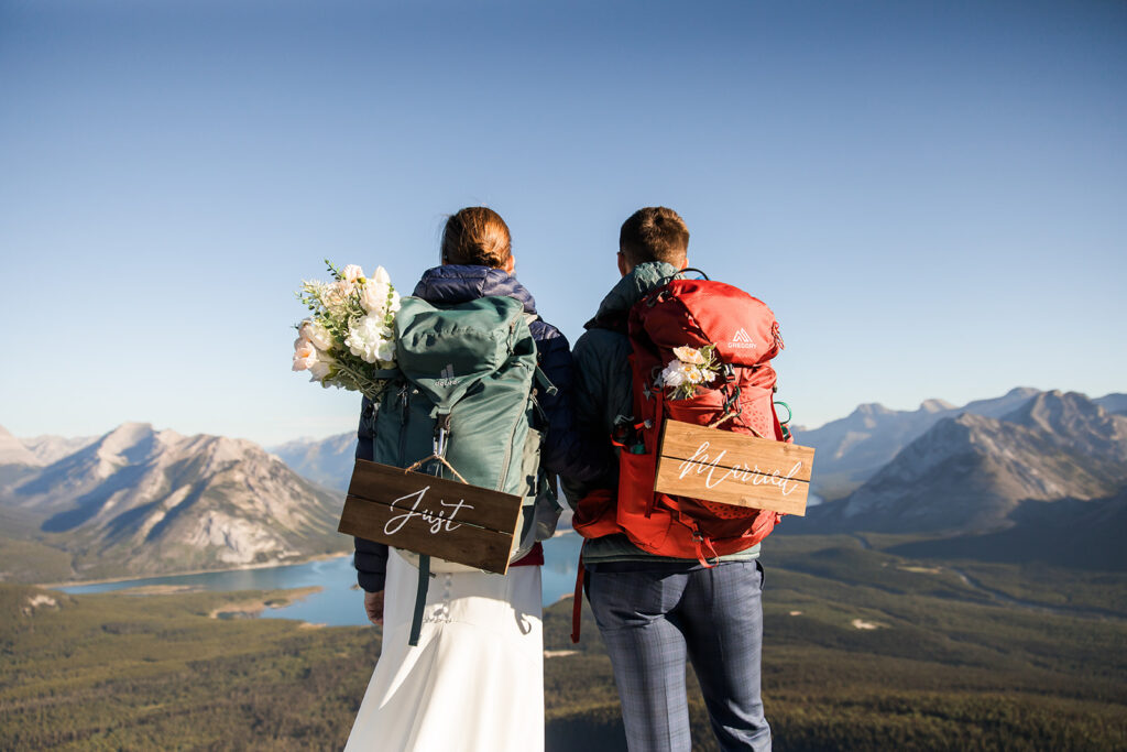 a same sex couple wears just married signs after eloping on tent ridge in kananaskis at sunrise