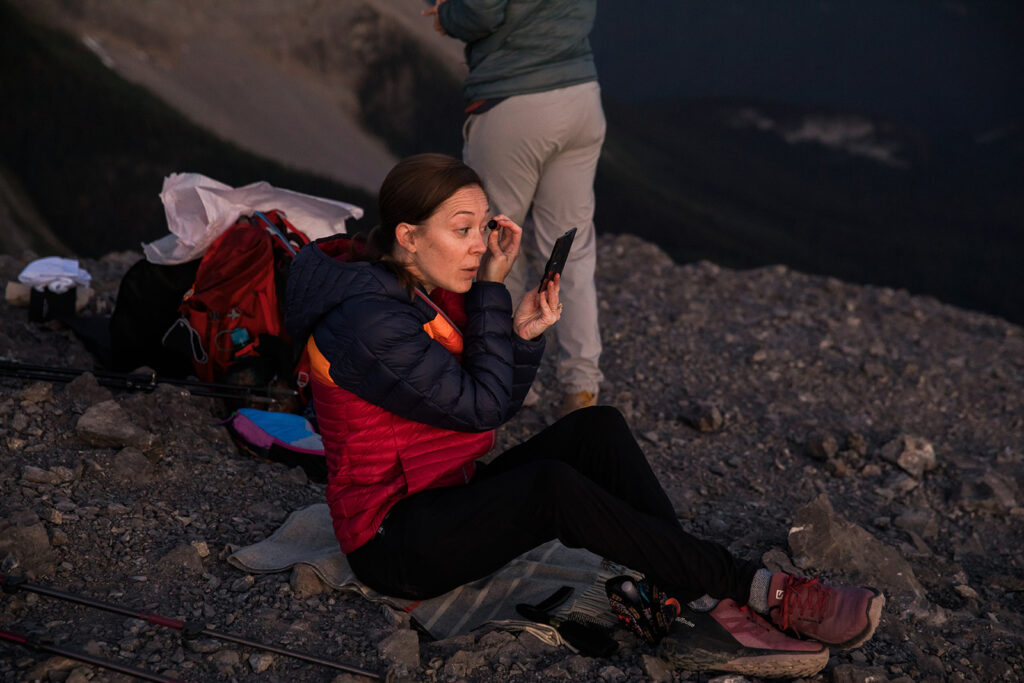 a bride doing her makeup in the dark for a sunrise hiking elopement